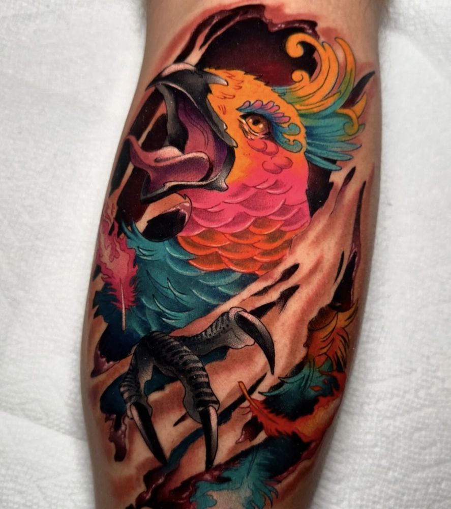 Neon color tattoo of a parrot tearing out of the skin